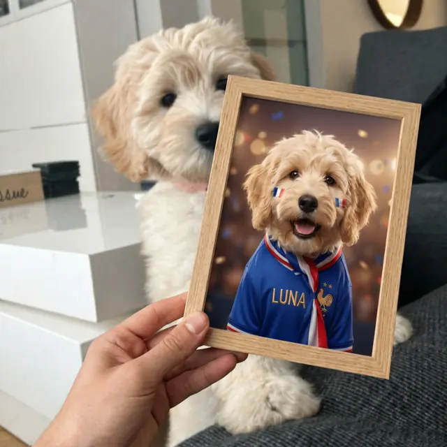 Homme tenant le portrait encadré de sa chienne cockapoo Luna en supportrice, avec la vraie chienne derrière